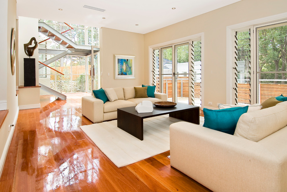 This is an example of a mid-sized contemporary formal open concept living room in Sunshine Coast with beige walls, medium hardwood floors and brown floor.