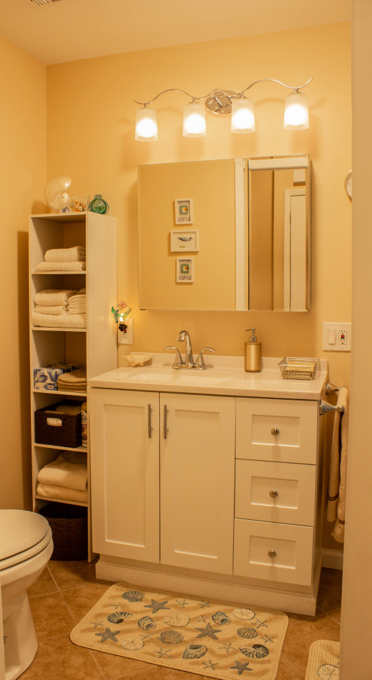 This is an example of a small transitional 3/4 bathroom in Other with shaker cabinets, white cabinets, an alcove shower, a two-piece toilet, beige walls, vinyl floors, an undermount sink, marble benchtops, brown floor, a shower curtain, white benchtops, a laundry, a single vanity and a freestanding vanity.