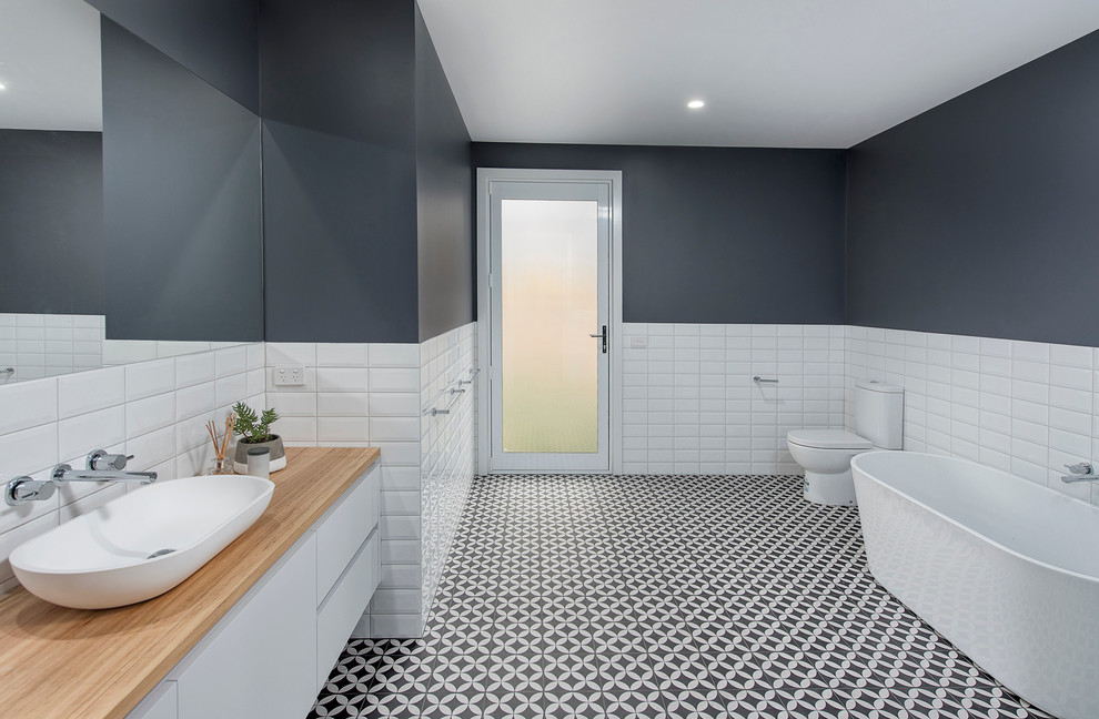 Design ideas for a large contemporary kids bathroom in Melbourne with flat-panel cabinets, white cabinets, a freestanding tub, a double shower, a two-piece toilet, black and white tile, ceramic tile, grey walls, ceramic floors, a console sink and wood benchtops.