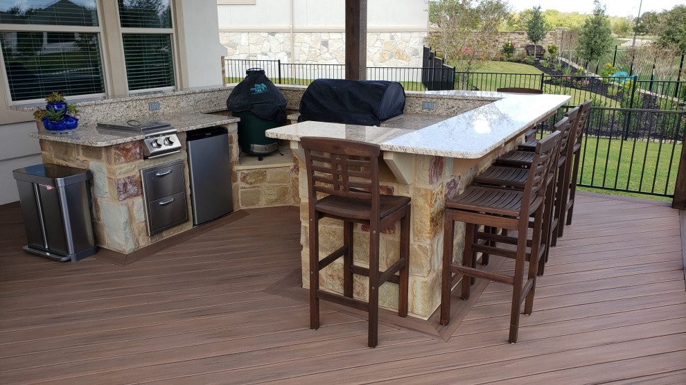 This is an example of a large eclectic backyard deck in Austin with an outdoor kitchen, a pergola and metal railing.