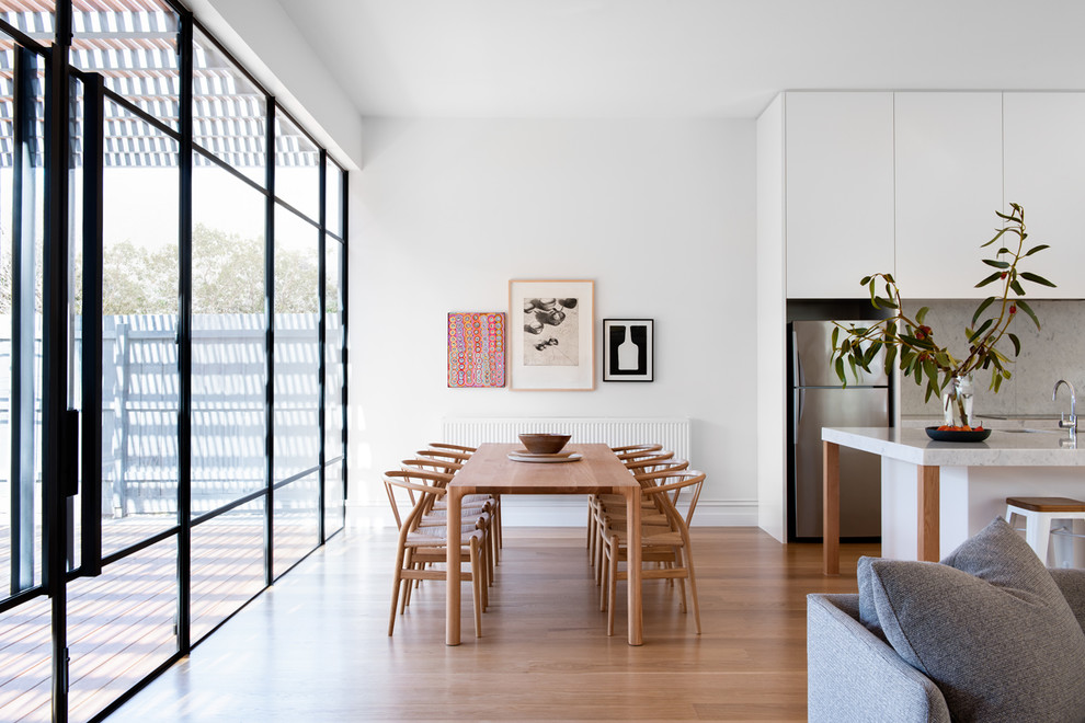 Contemporary open plan dining in Melbourne with white walls, light hardwood floors, no fireplace and beige floor.