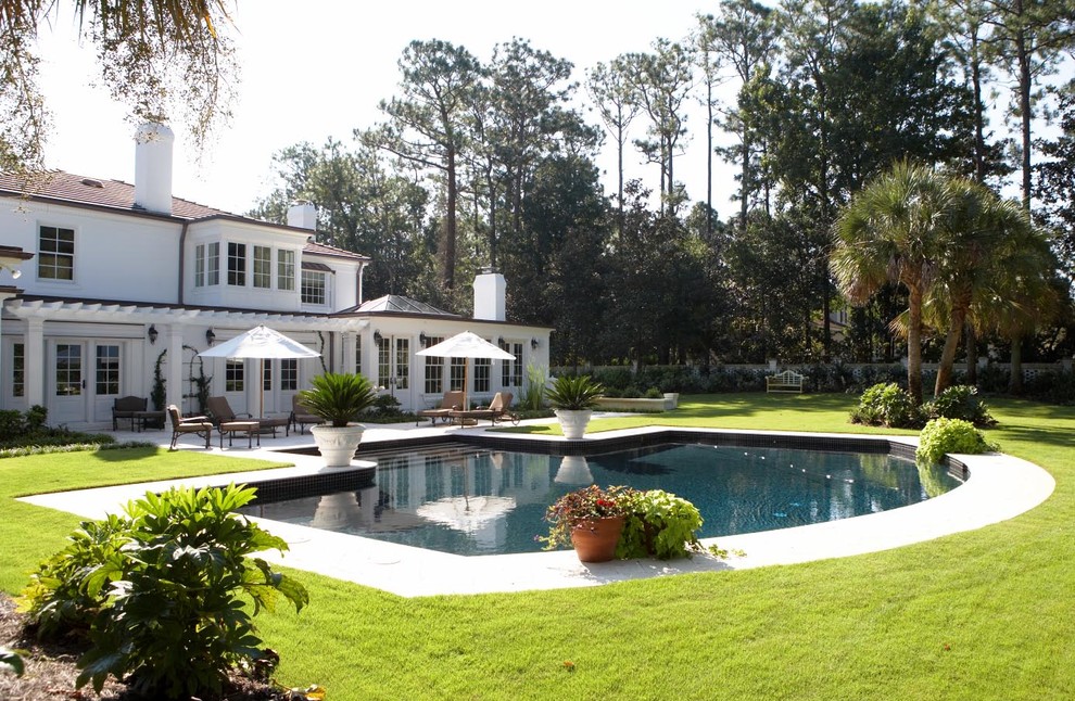 Large traditional backyard custom-shaped pool in Other with concrete pavers.