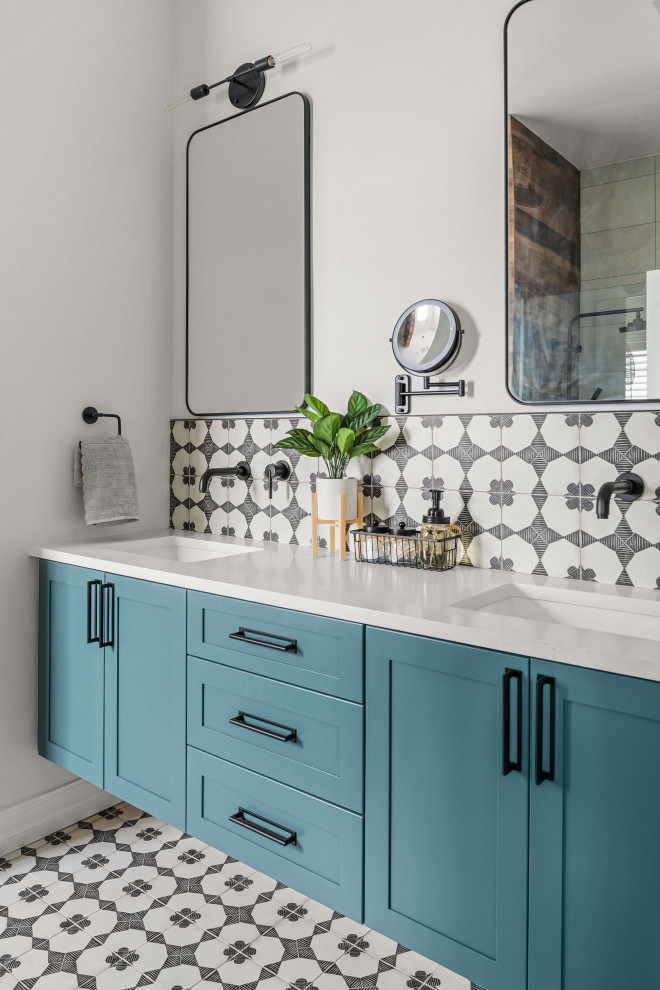 This is an example of a mid-sized eclectic master bathroom in Orlando with shaker cabinets, blue cabinets, a drop-in tub, a curbless shower, a two-piece toilet, black and white tile, porcelain tile, white walls, porcelain floors, an undermount sink, engineered quartz benchtops, black floor, a hinged shower door, white benchtops, a shower seat, a double vanity and a floating vanity.