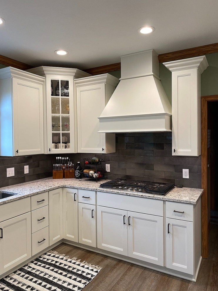 This is an example of a large traditional l-shaped kitchen/diner in Cleveland with a submerged sink, shaker cabinets, white cabinets, engineered stone countertops, grey splashback, metro tiled splashback, stainless steel appliances, vinyl flooring, a breakfast bar, brown floors and grey worktops.