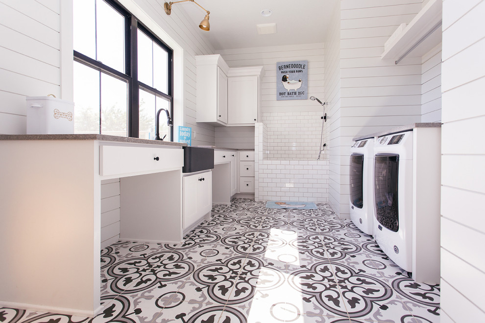 Inspiration for a mid-sized country laundry room in Portland with a drop-in sink, white cabinets, window splashback, white walls, multi-coloured floor, grey benchtop and a side-by-side washer and dryer.