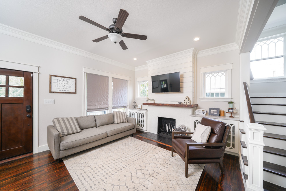 This is an example of a transitional living room in Other with grey walls, dark hardwood floors, a standard fireplace, a brick fireplace surround and brown floor.