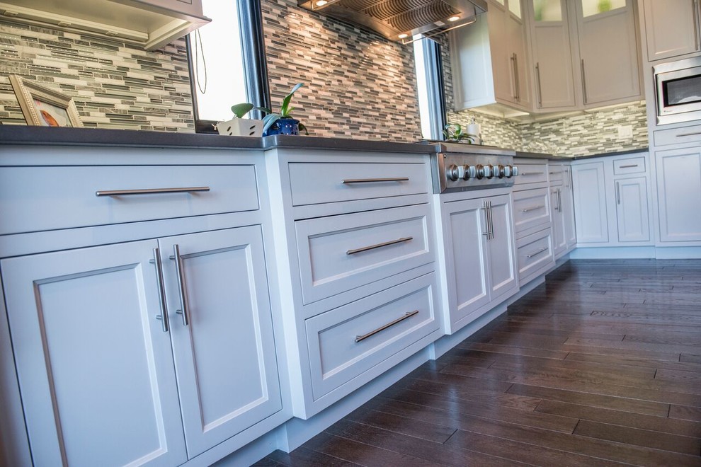 Large transitional l-shaped dark wood floor open concept kitchen photo with a double-bowl sink, beaded inset cabinets, white cabinets, granite countertops, multicolored backsplash, matchstick tile backsplash, stainless steel appliances and an island