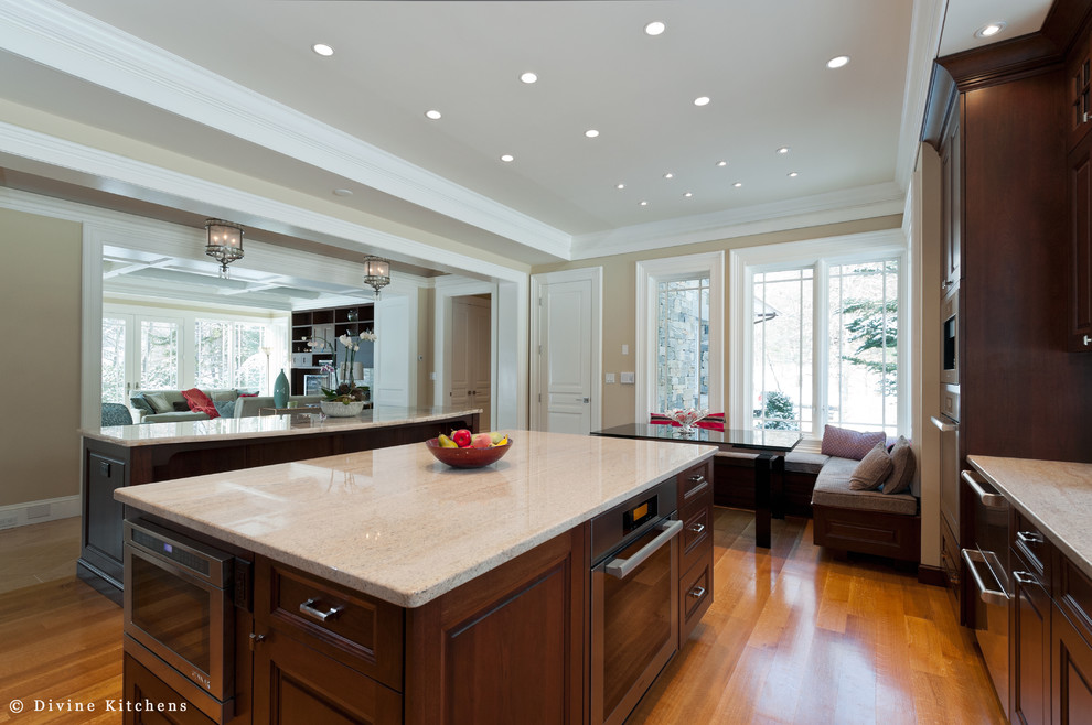 Inspiration for a large traditional u-shaped eat-in kitchen in Boston with an undermount sink, raised-panel cabinets, dark wood cabinets, beige splashback, stainless steel appliances, light hardwood floors, multiple islands and quartzite benchtops.