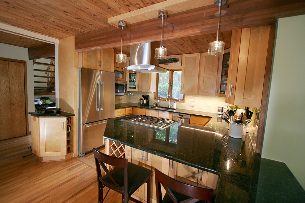 Small transitional l-shaped porcelain tile eat-in kitchen photo with shaker cabinets, light wood cabinets, granite countertops, beige backsplash, glass tile backsplash, stainless steel appliances and a peninsula