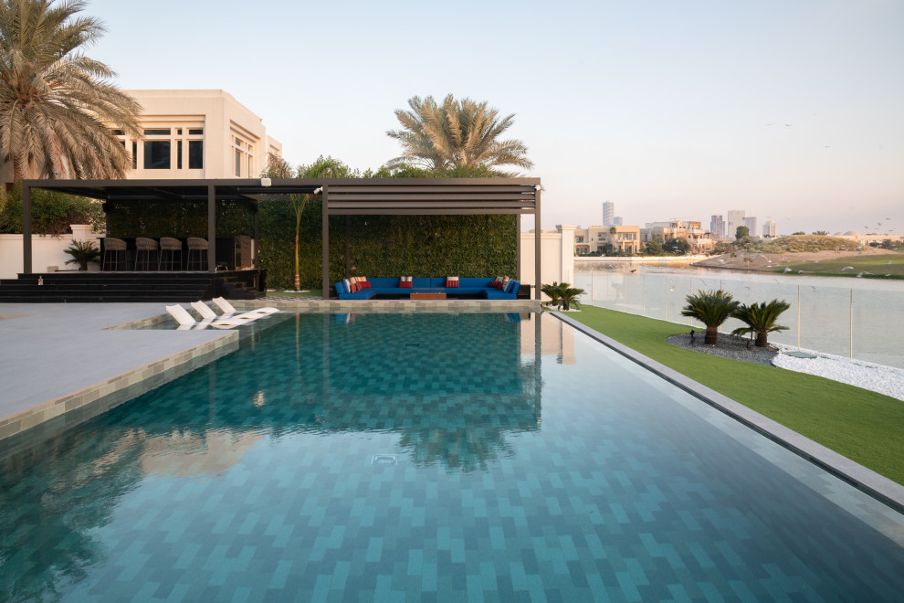 Ispirazione per una piscina tropicale personalizzata di medie dimensioni e dietro casa con paesaggistica bordo piscina e piastrelle