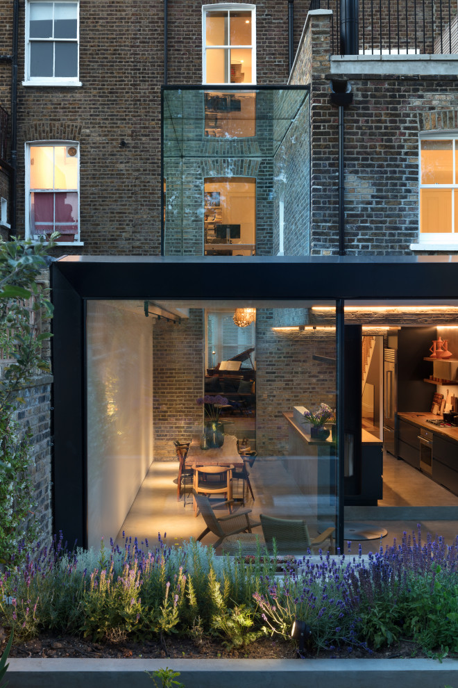 This is an example of a large contemporary black townhouse exterior in London with four or more storeys, metal siding and a gable roof.