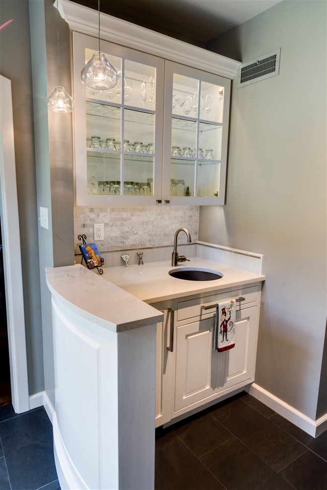 Photo of a small contemporary single-wall wet bar in Wichita with white cabinets, an undermount sink, raised-panel cabinets, marble benchtops, grey splashback, stone tile splashback and slate floors.