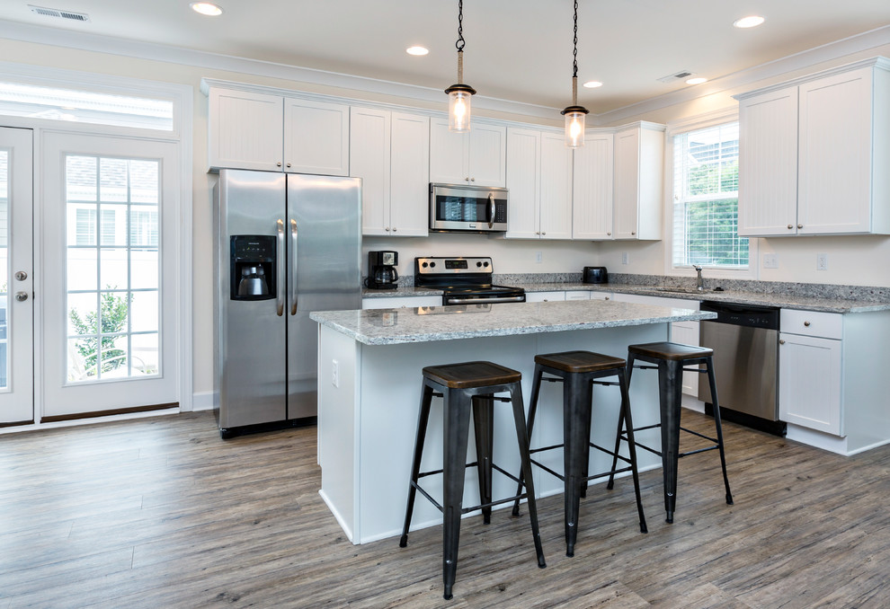 Photo of a mid-sized beach style l-shaped eat-in kitchen in Other with an undermount sink, shaker cabinets, white cabinets, granite benchtops, stainless steel appliances, dark hardwood floors, with island and beige floor.