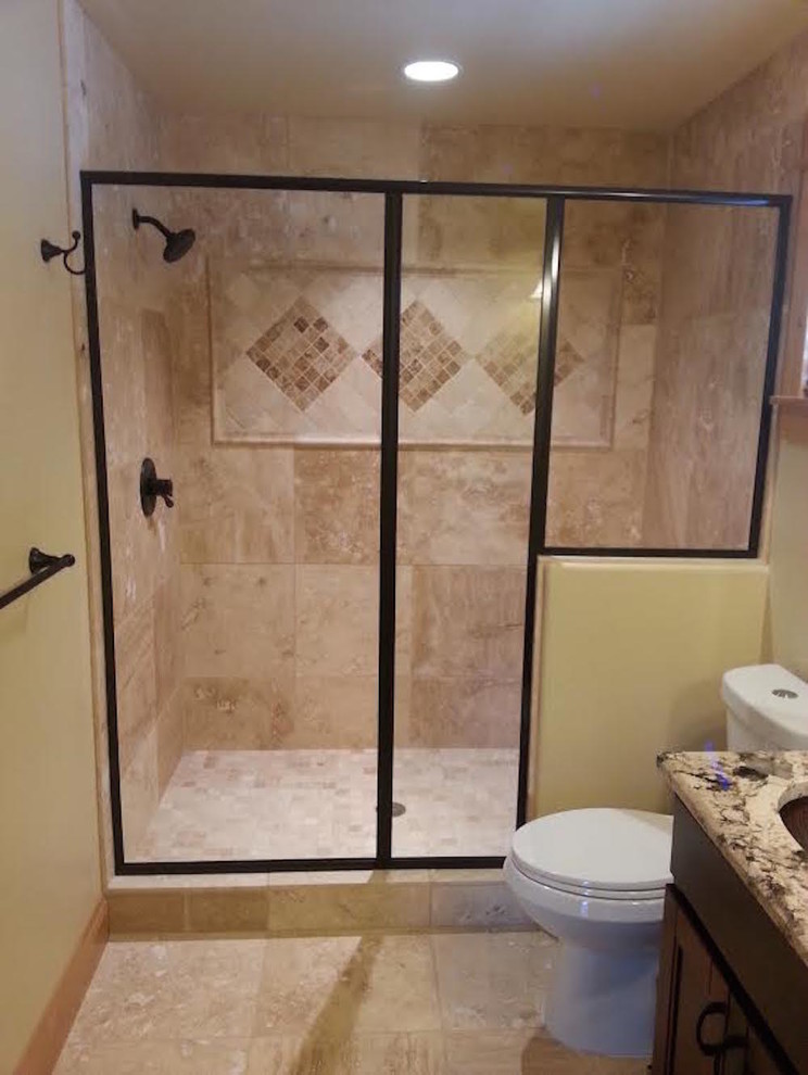 Alcove shower - transitional beige tile and porcelain tile limestone floor alcove shower idea in Denver with recessed-panel cabinets, dark wood cabinets, a two-piece toilet, yellow walls, an undermount sink and a hinged shower door