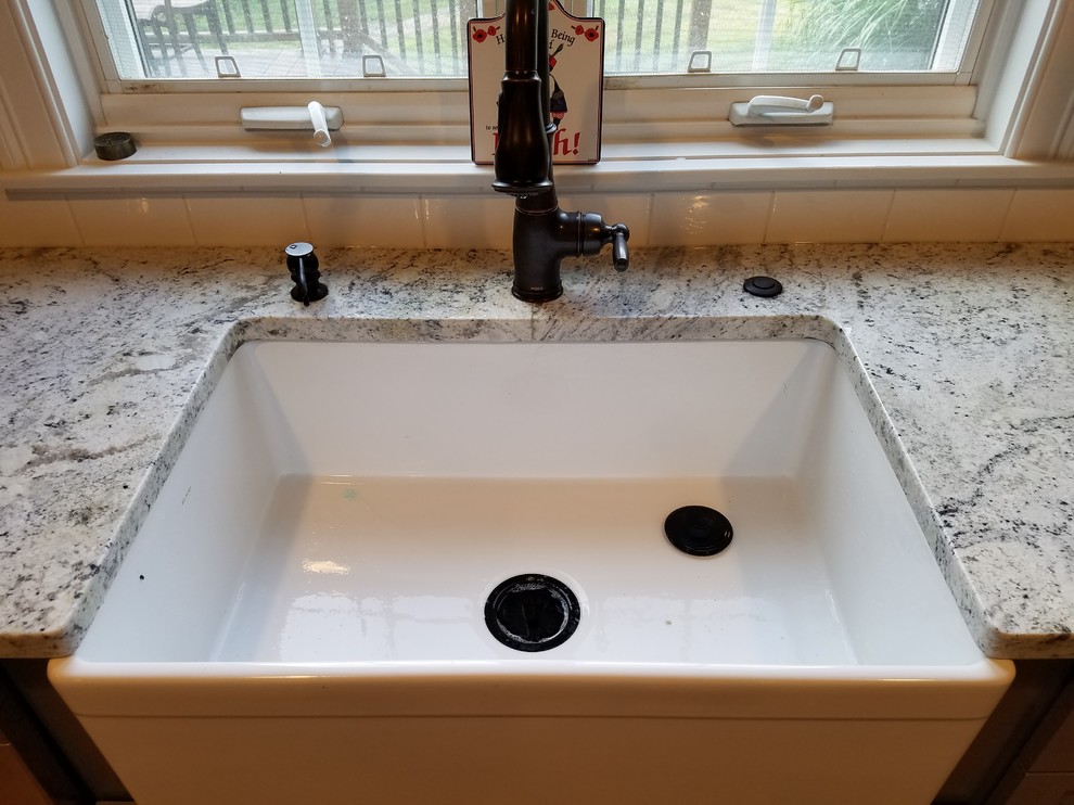 Mid-sized transitional galley light wood floor and brown floor eat-in kitchen photo with a farmhouse sink, recessed-panel cabinets, gray cabinets, wood countertops, white backsplash, subway tile backsplash, stainless steel appliances and an island