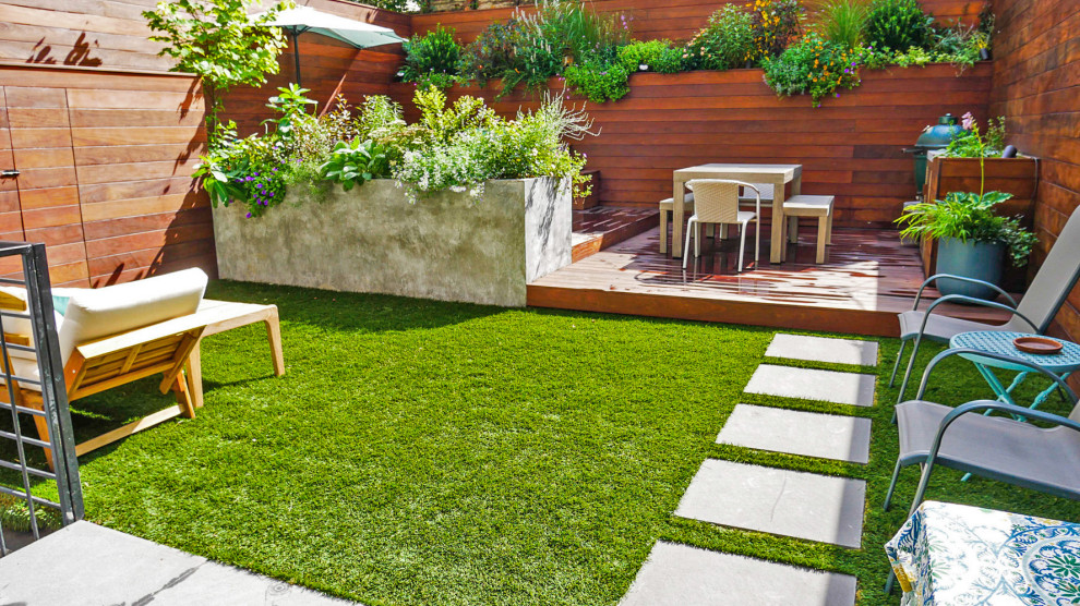 This is an example of a small contemporary backyard full sun garden in New York with with privacy feature and decking.