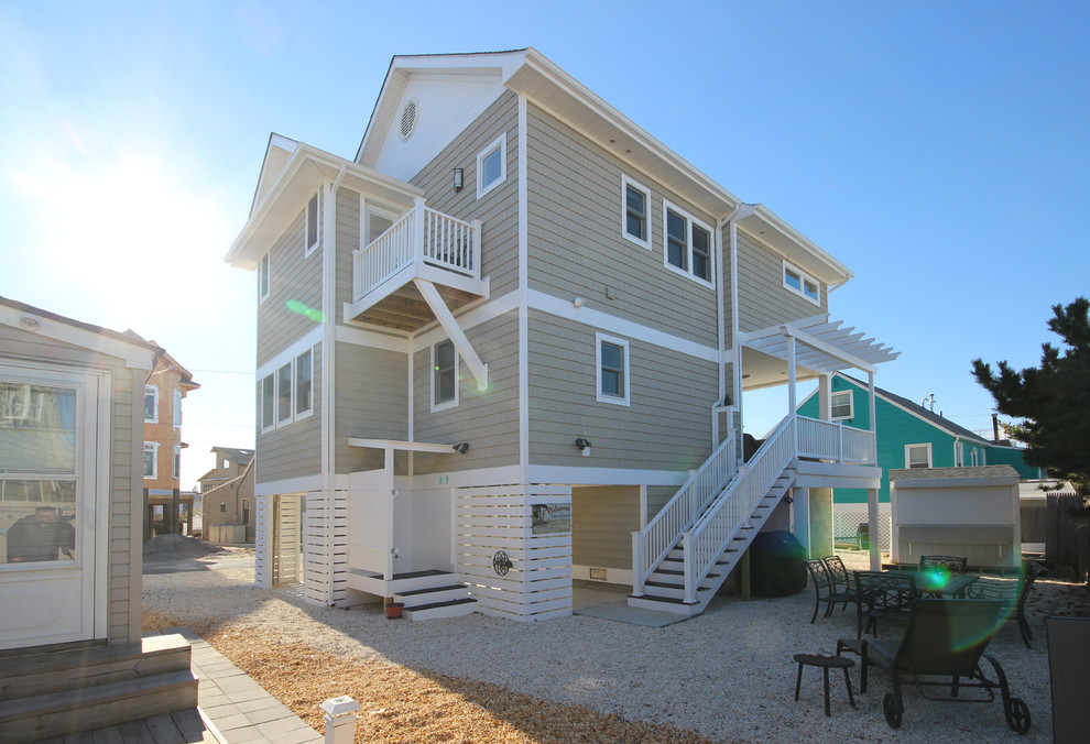Photo of a large beach style three-storey grey house exterior in New York with wood siding, a gable roof and a shingle roof.