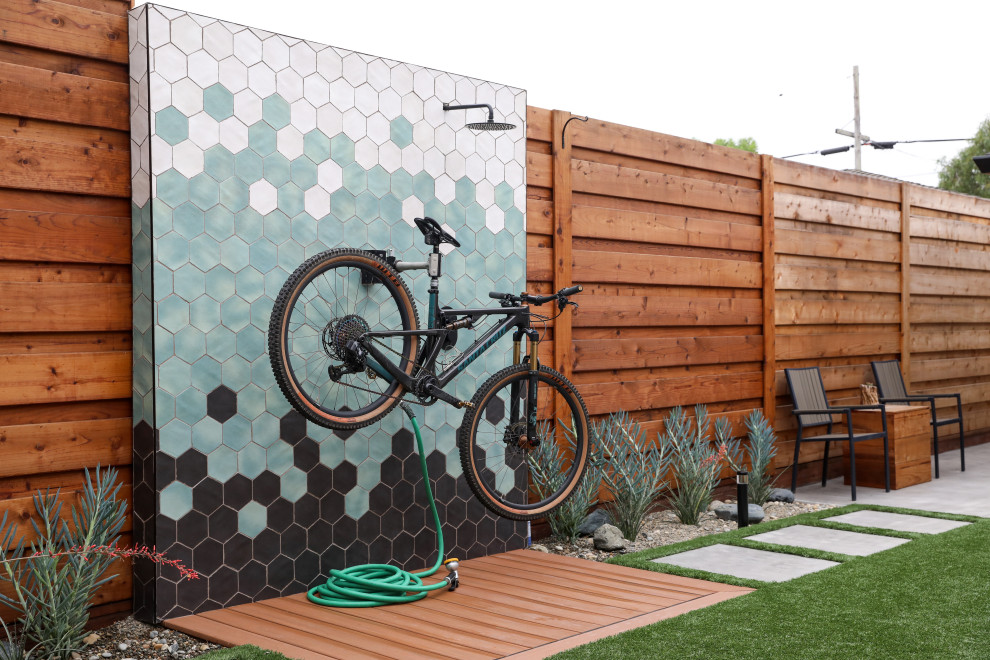 Cette image montre un xéropaysage latéral minimaliste de taille moyenne et l'été avec une exposition ensoleillée, des pavés en béton et une clôture en métal.
