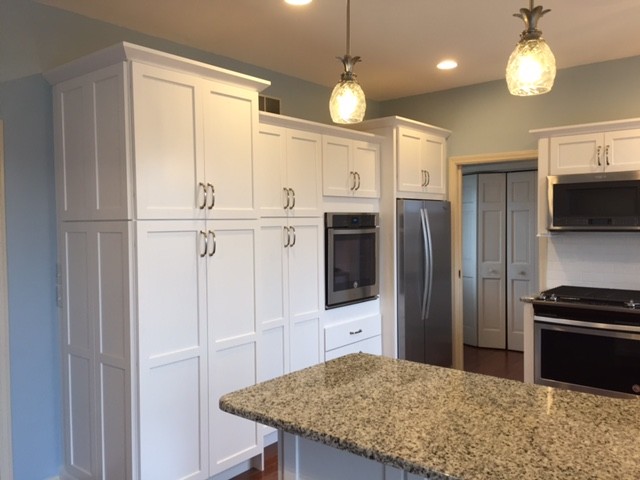 Eat-in kitchen - mid-sized transitional u-shaped medium tone wood floor and brown floor eat-in kitchen idea in Boston with a single-bowl sink, shaker cabinets, white cabinets, granite countertops, white backsplash, porcelain backsplash, stainless steel appliances and a peninsula