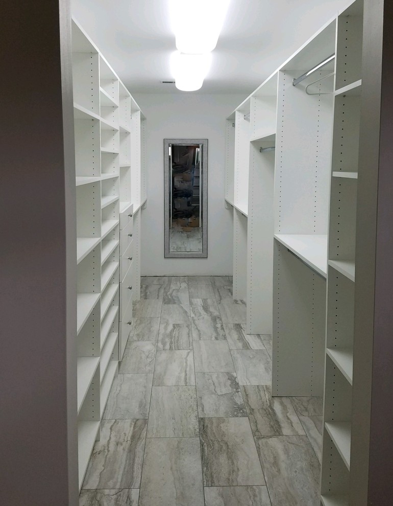 Design ideas for a mid-sized transitional gender-neutral walk-in wardrobe in Indianapolis with flat-panel cabinets, white cabinets and light hardwood floors.