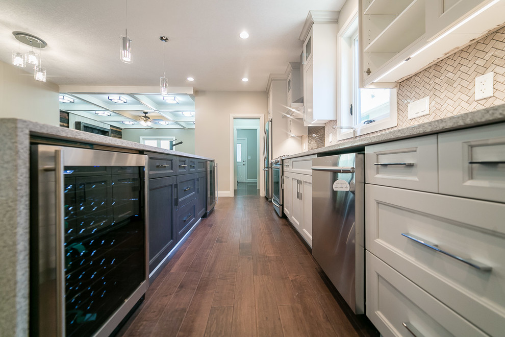 Inspiration for a mid-sized transitional galley dark wood floor kitchen pantry remodel in Edmonton with an undermount sink, shaker cabinets, white cabinets, granite countertops, multicolored backsplash, matchstick tile backsplash, stainless steel appliances and an island