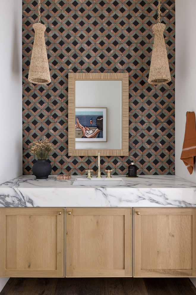Example of a mid-sized southwest white tile and marble tile medium tone wood floor and brown floor powder room design in Other with shaker cabinets, light wood cabinets, a one-piece toilet, white walls, an undermount sink, marble countertops, white countertops and a built-in vanity