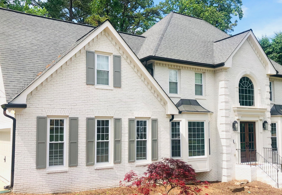 Photo of a large country three-storey brick white house exterior in Atlanta with a gambrel roof, a shingle roof, a grey roof and clapboard siding.