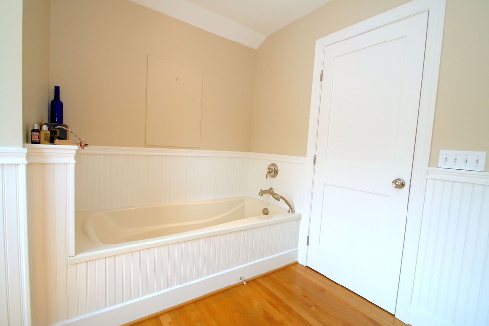 Large beach style 3/4 bathroom in New York with an alcove tub, a corner shower, yellow walls, medium hardwood floors, a pedestal sink, brown floor and a hinged shower door.