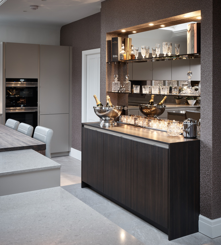 Photo of a large contemporary l-shaped eat-in kitchen in Other with a drop-in sink, flat-panel cabinets, beige cabinets, quartzite benchtops, brown splashback, mirror splashback, black appliances, porcelain floors, with island and grey floor.