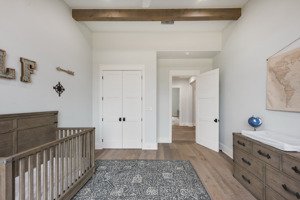 Ejemplo de habitación de bebé neutra campestre grande con paredes blancas, suelo de madera clara, suelo beige y vigas vistas