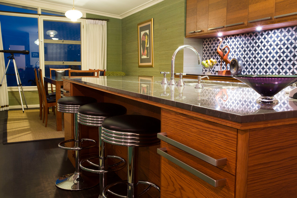 This is an example of a mid-sized midcentury galley eat-in kitchen in Wollongong with an undermount sink, flat-panel cabinets, medium wood cabinets, limestone benchtops, black splashback, ceramic splashback, stainless steel appliances, dark hardwood floors and with island.