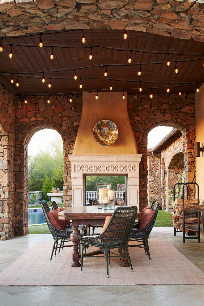 Photo of a backyard patio in Phoenix with tile, a roof extension and with fireplace.