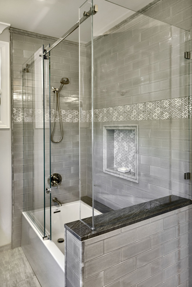 На фото: большая серо-белая ванная комната в стиле неоклассика (современная классика) с ванной в нише, душем в нише, серой плиткой, плиткой кабанчик, серыми стенами, полом из керамогранита, серым полом, душем с раздвижными дверями, серой столешницей и нишей