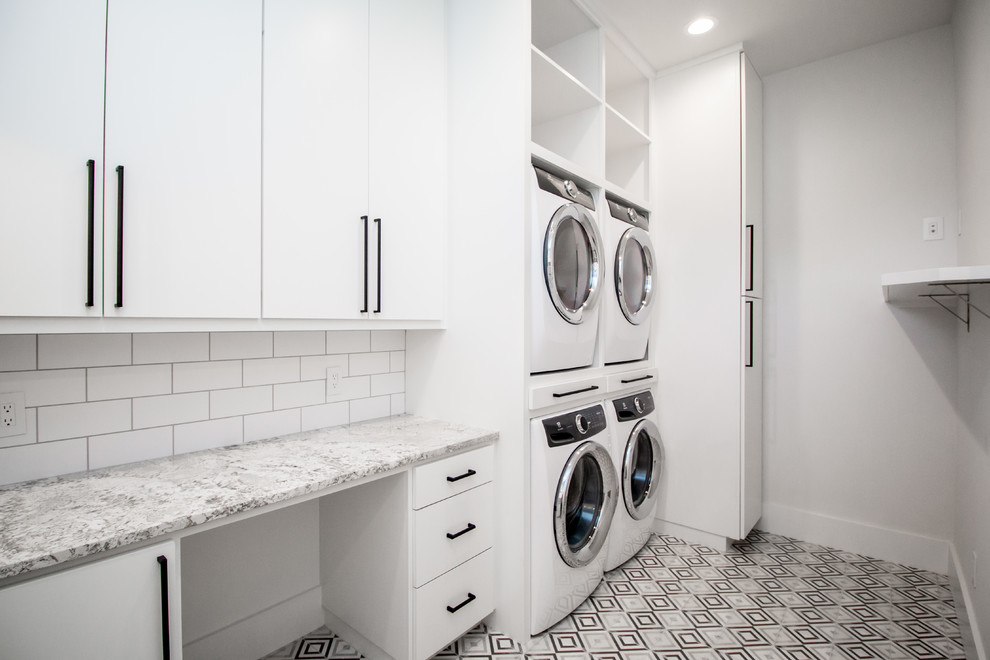Mid-sized contemporary single-wall utility room in Other with flat-panel cabinets, white cabinets, granite benchtops, white walls, a stacked washer and dryer and multi-coloured floor.