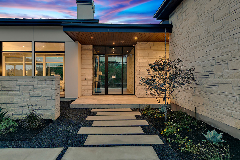 This is an example of a large contemporary one-storey white house exterior in Austin with stone veneer and a metal roof.
