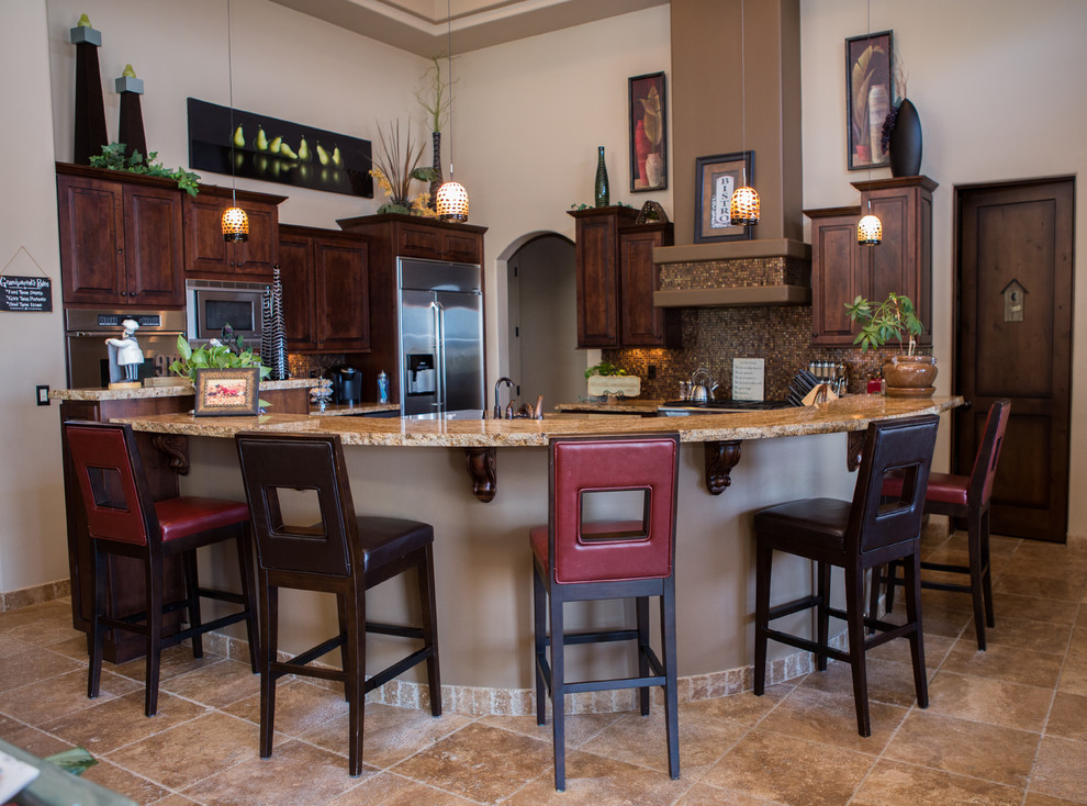 Example of a large transitional u-shaped travertine floor eat-in kitchen design in Phoenix with raised-panel cabinets, dark wood cabinets, granite countertops, multicolored backsplash, glass tile backsplash, stainless steel appliances and an island