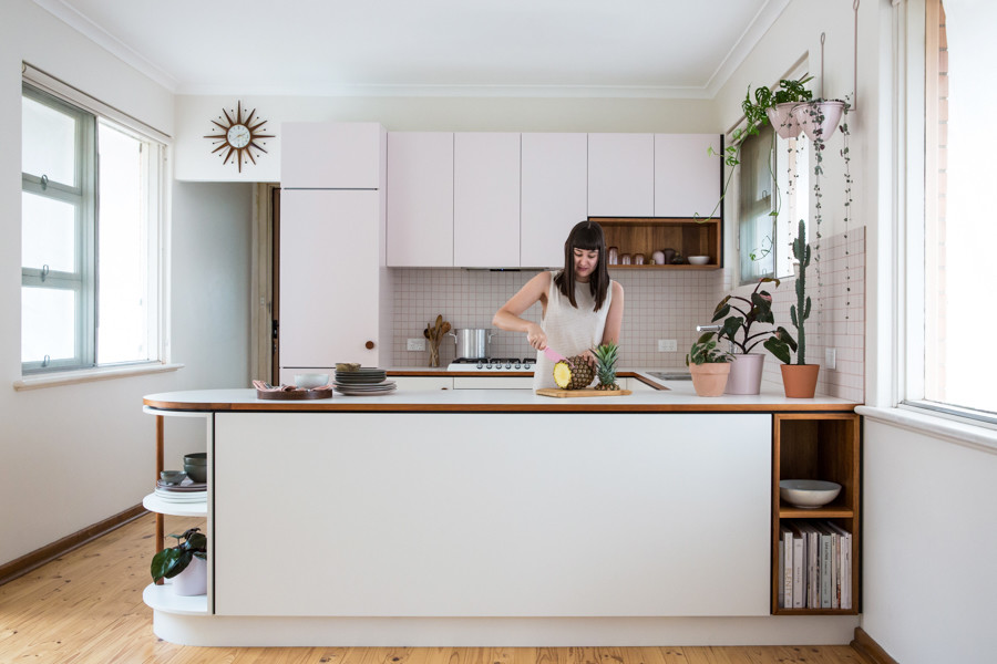 This is an example of a small midcentury u-shaped open plan kitchen in Adelaide with flat-panel cabinets, laminate benchtops, white splashback, ceramic splashback, white appliances and light hardwood floors.