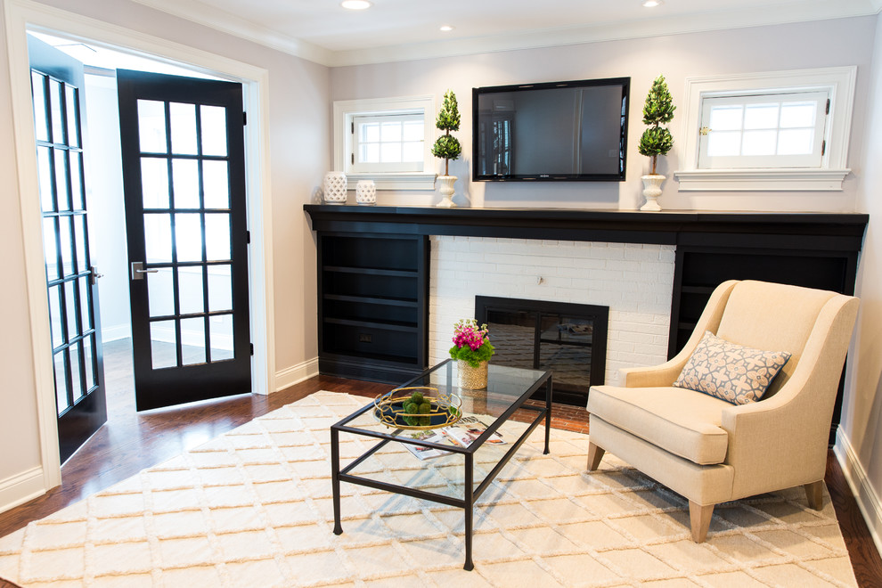 Photo of a small traditional formal enclosed living room in Chicago with grey walls, medium hardwood floors, a standard fireplace, a brick fireplace surround and a wall-mounted tv.