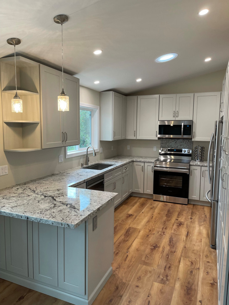 Photo of a small country u-shaped eat-in kitchen in San Luis Obispo with an undermount sink, shaker cabinets, grey cabinets, granite benchtops, grey splashback, stainless steel appliances, light hardwood floors, a peninsula, brown floor, multi-coloured benchtop and vaulted.