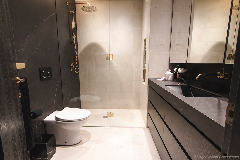 Inspiration for a mid-sized modern 3/4 bathroom in Sydney with flat-panel cabinets, dark wood cabinets, a wall-mount toilet, gray tile, porcelain tile, grey walls, porcelain floors, a vessel sink, tile benchtops, beige floor and grey benchtops.