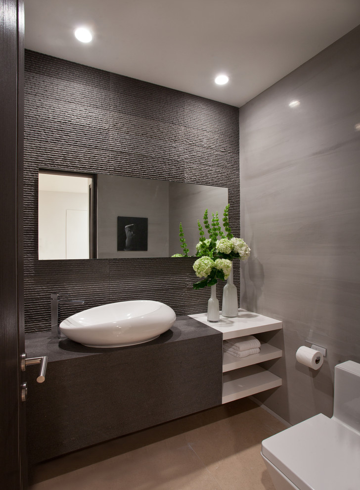 Inspiration for a mid-sized contemporary powder room in Miami with a vessel sink, open cabinets, white cabinets, wood benchtops, a one-piece toilet, gray tile, grey walls, ceramic floors, beige floor and grey benchtops.