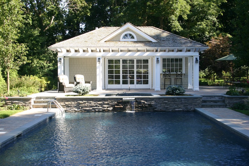 Photo of a large arts and crafts backyard rectangular lap pool in New York with a pool house and natural stone pavers.