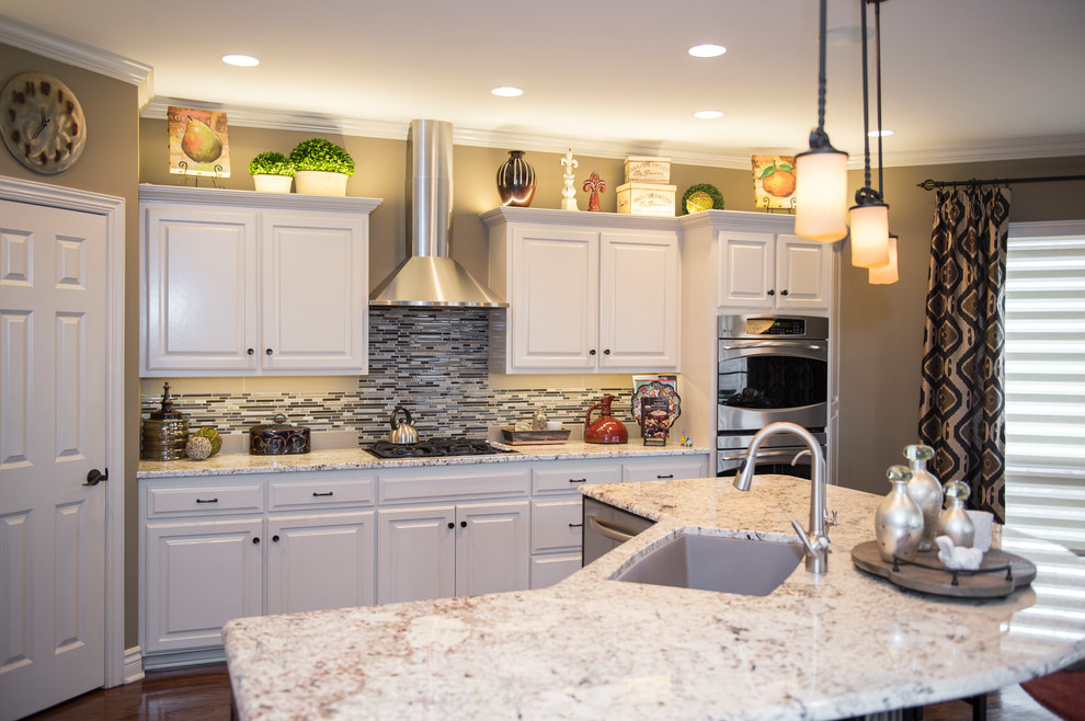 Large transitional dark wood floor open concept kitchen photo in Omaha with an undermount sink, raised-panel cabinets, white cabinets, granite countertops, brown backsplash, glass tile backsplash, stainless steel appliances and an island