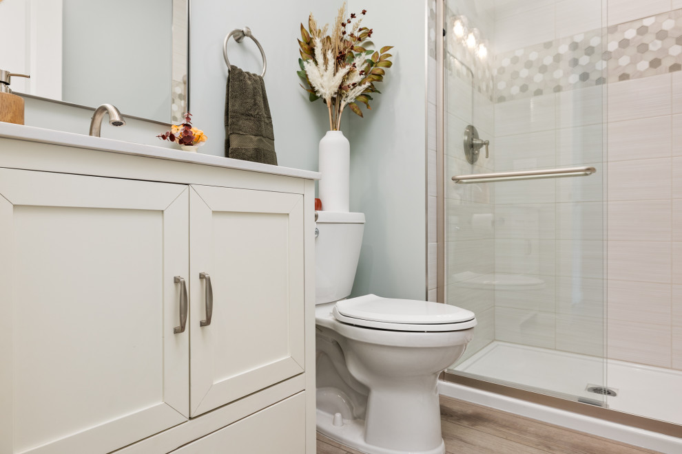 Exemple d'une salle de bain chic de taille moyenne avec un placard à porte shaker, des portes de placard blanches, WC à poser, un carrelage beige, des carreaux de porcelaine, un mur bleu, un sol en vinyl, un lavabo encastré, un plan de toilette en quartz modifié, un sol beige, une cabine de douche à porte coulissante, un plan de toilette blanc, meuble simple vasque et meuble-lavabo sur pied.
