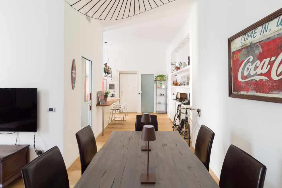 This is an example of a large industrial dining room in Milan with white walls and light hardwood floors.