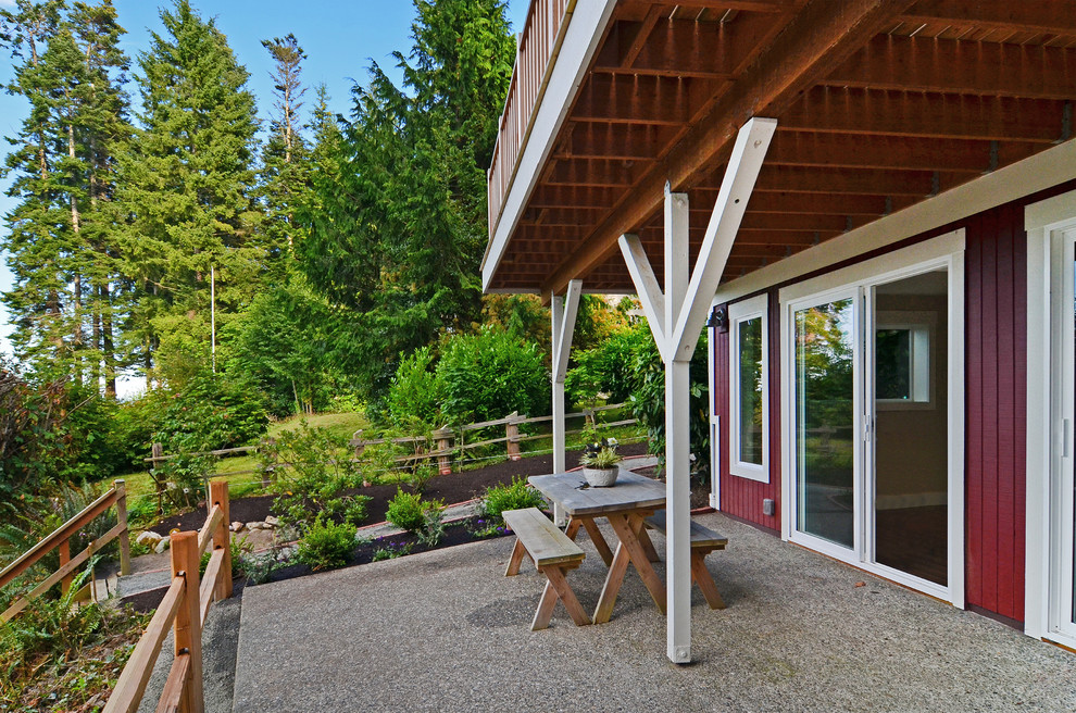 This is an example of a mid-sized country backyard patio in Seattle with concrete slab and a roof extension.