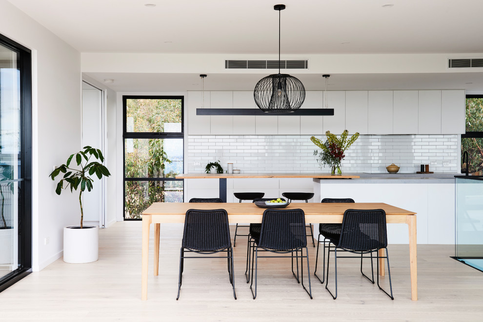 This is an example of a mid-sized modern open plan dining in Geelong with white walls, light hardwood floors and brown floor.