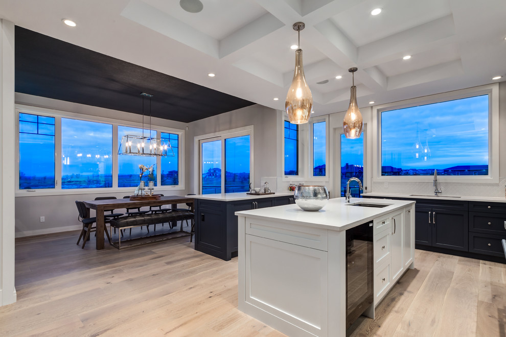 Kitchen - transitional u-shaped light wood floor kitchen idea in Calgary with an undermount sink, shaker cabinets, blue cabinets, quartzite countertops, white backsplash, porcelain backsplash, stainless steel appliances and an island