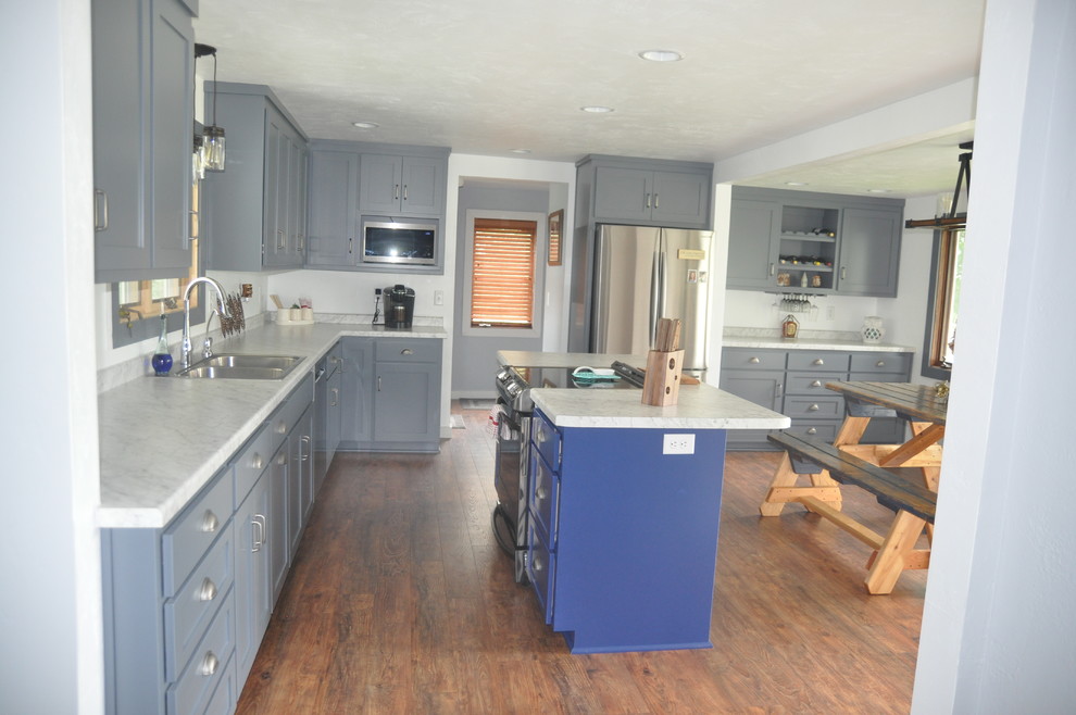 Inspiration for a mid-sized transitional l-shaped medium tone wood floor and brown floor eat-in kitchen remodel with a double-bowl sink, shaker cabinets, gray cabinets, marble countertops, white backsplash, stainless steel appliances, an island and gray countertops