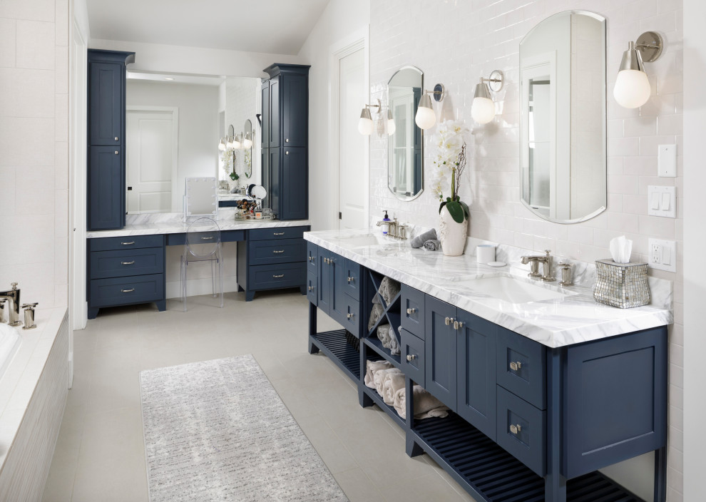 Photo of a transitional bathroom in Houston with shaker cabinets, blue cabinets, a drop-in tub, white walls, an undermount sink, grey floor, white benchtops, a double vanity, a freestanding vanity and vaulted.